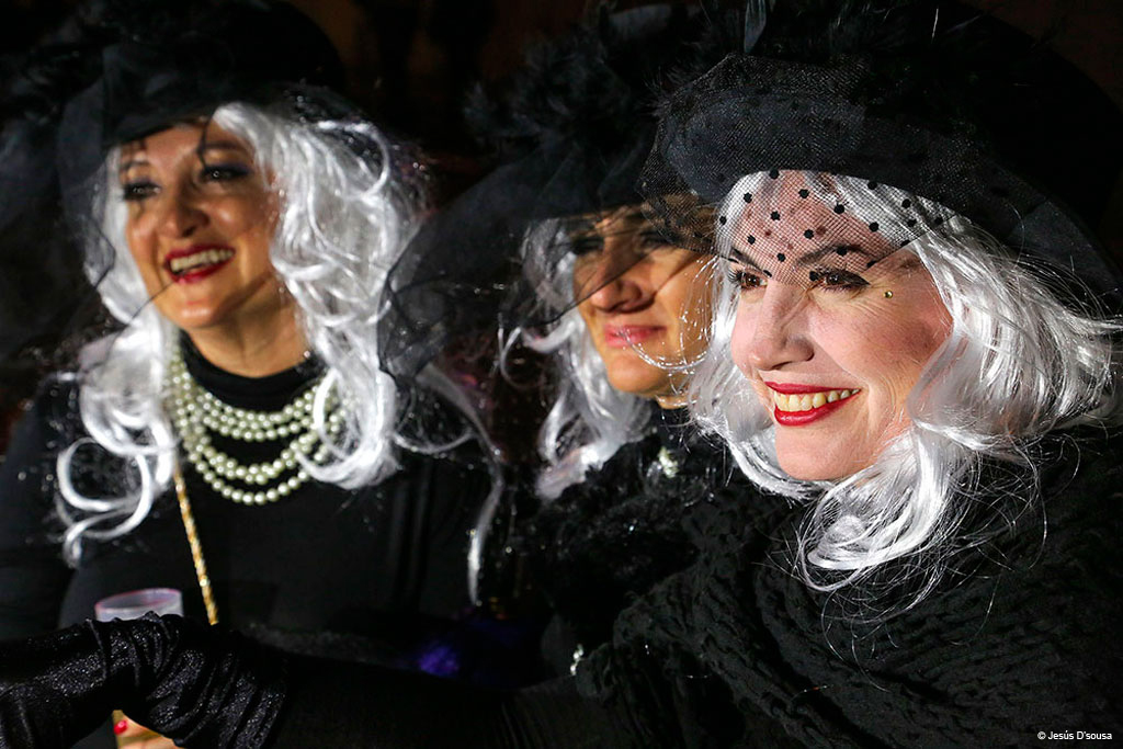Des gens déguisés en perruques blanches et chapeaux noirs au carnaval de Tenerife.