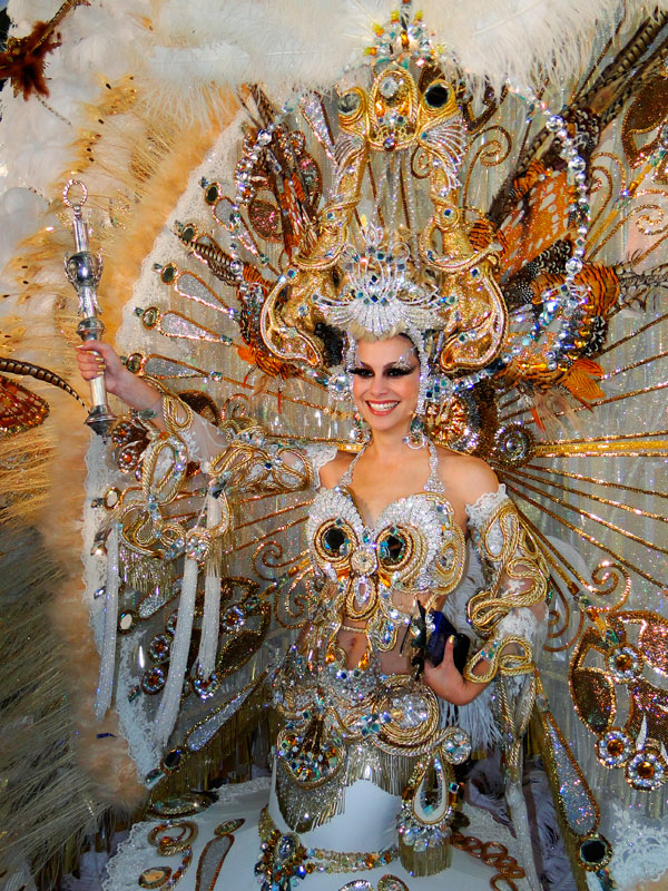 Personne en costume coloré et élaboré du Carnaval de Tenerife, tenant un sceptre.
