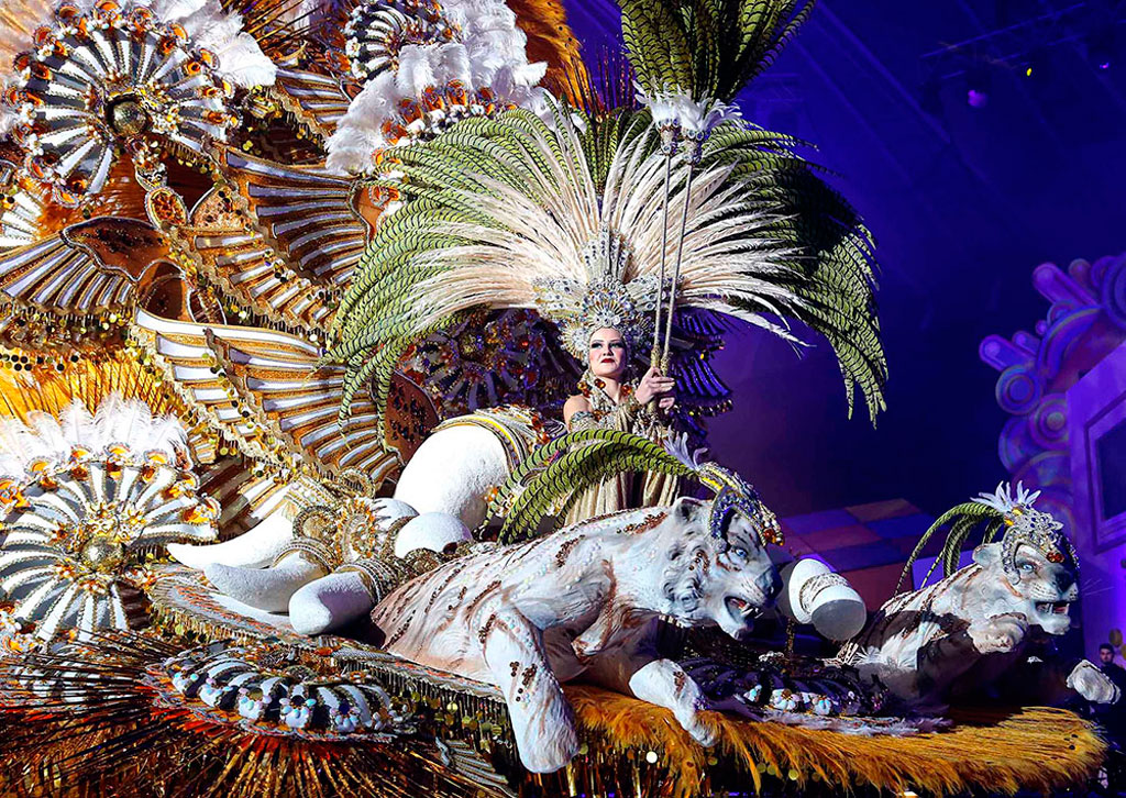 Carnaval à Tenerife avec une personne sur un char orné de plumes et de figures animales.