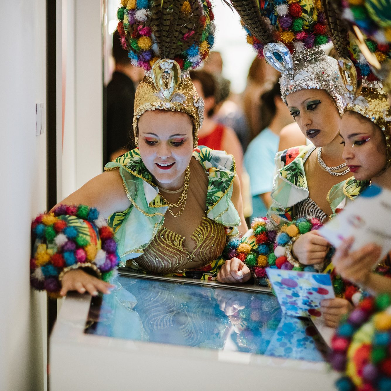 Des personnes en costumes colorés de carnaval interagissent avec un écran tactile à Tenerife.
