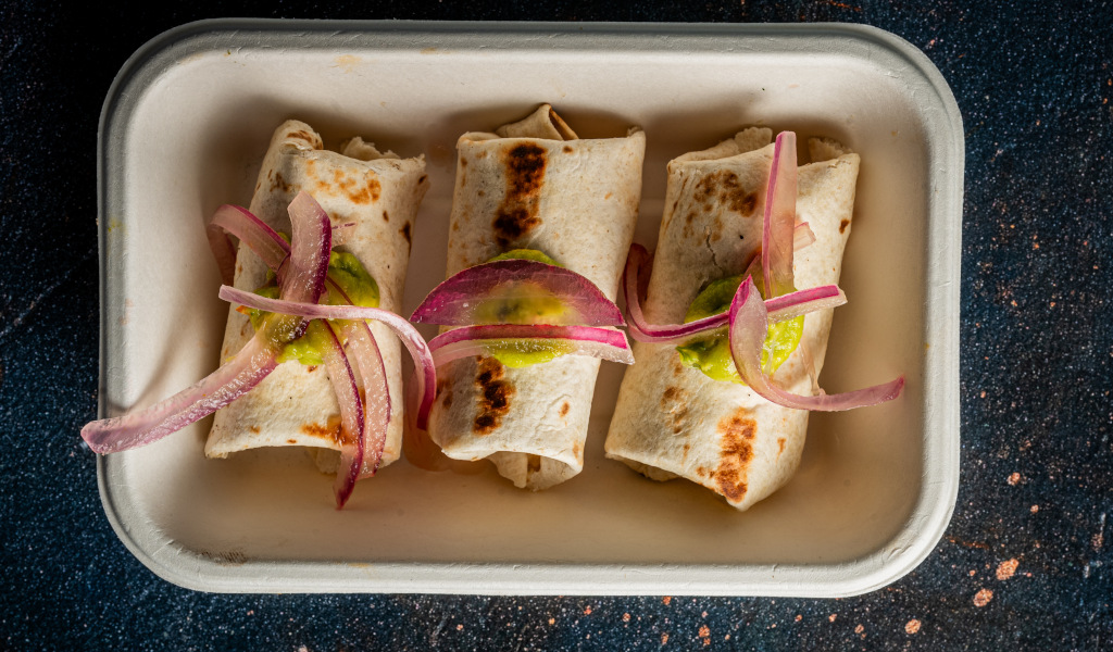 Trois burritos avec oignon rouge et salsa verde sur une assiette rectangulaire à Tenerife.