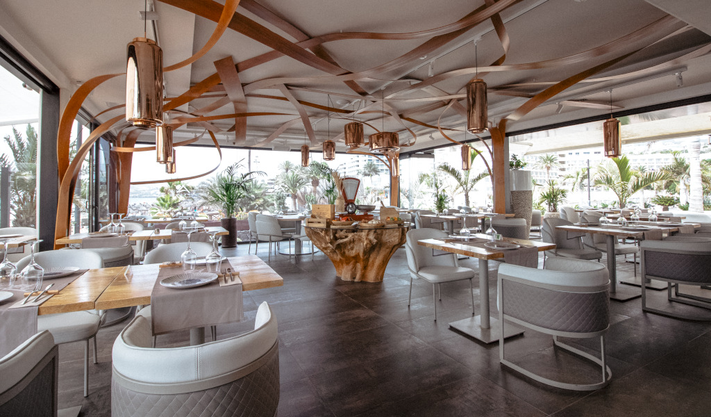 Restaurant moderne à la décoration élégante à Tenerife, des tables disposées près de grandes fenêtres.