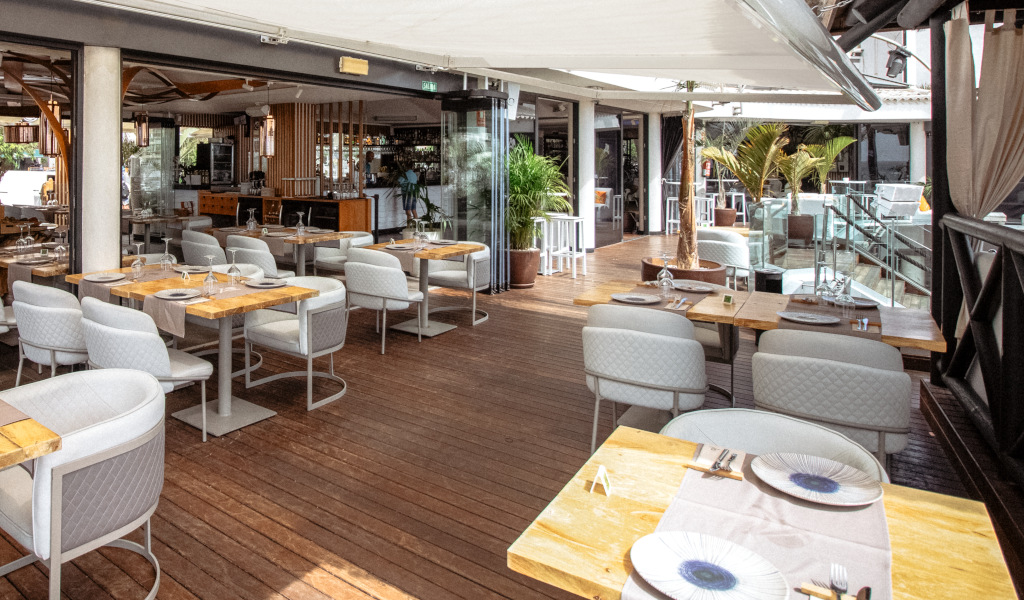 Terrasse de restaurant à Tenerife avec tables et chaises, décoration moderne.
