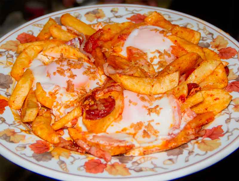 Des frites aux œufs et au chorizo sur une assiette décorée à Tenerife.