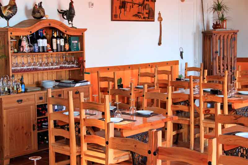 Restaurant à Tenerife avec tables et chaises en bois, et étagère avec verres.