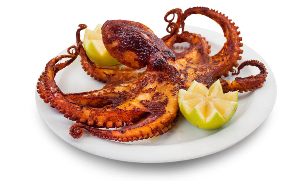 Du poulpe grillé servi avec des quartiers de citron sur une assiette blanche à Tenerife.