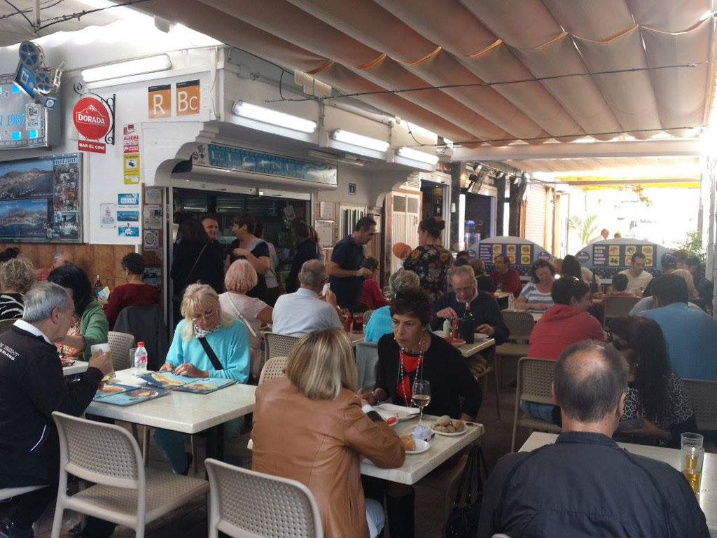 Des gens dînant dans un restaurant à Tenerife, avec un menu et une décoration visibles.