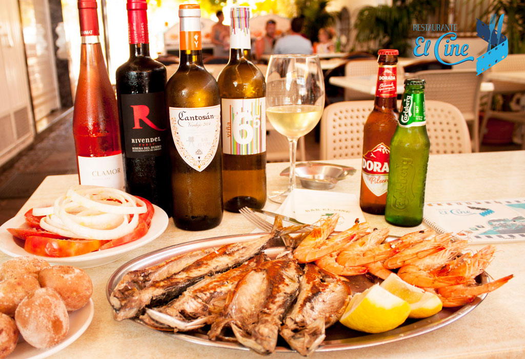 Plat de poisson et crevettes avec bouteilles de vin et bière au restaurant El Cine, Tenerife.
