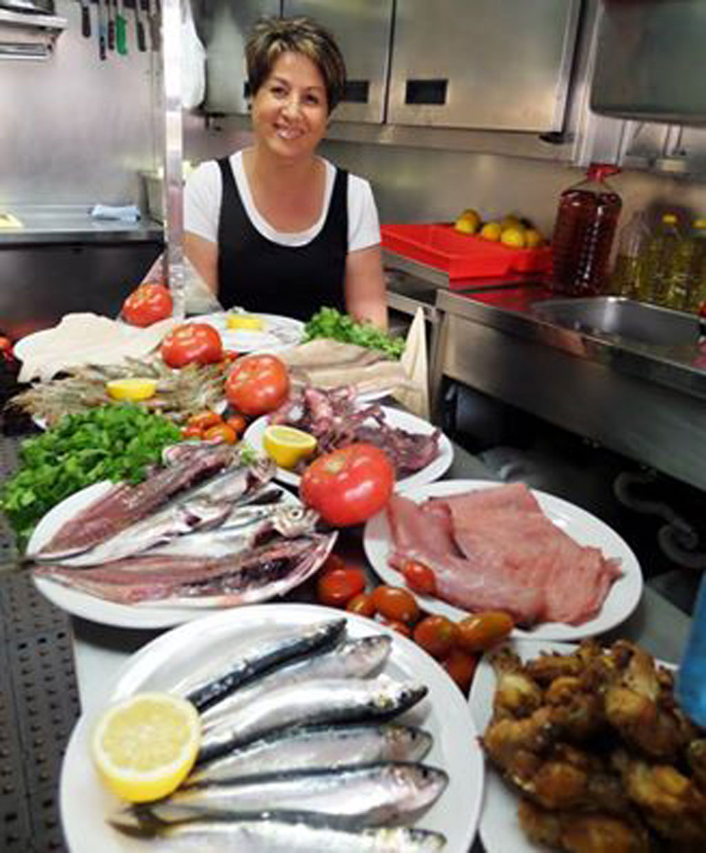 Personne en cuisine avec des plats de poisson, tomate et citron à Tenerife.