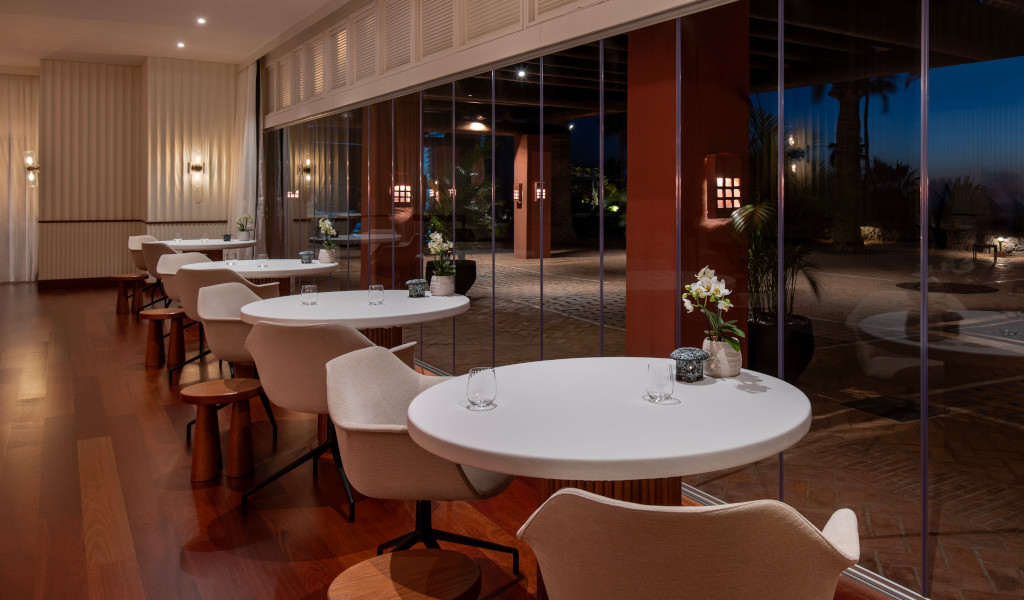 Des tables à manger et des chaises à côté de grandes fenêtres dans un restaurant élégant à Tenerife.