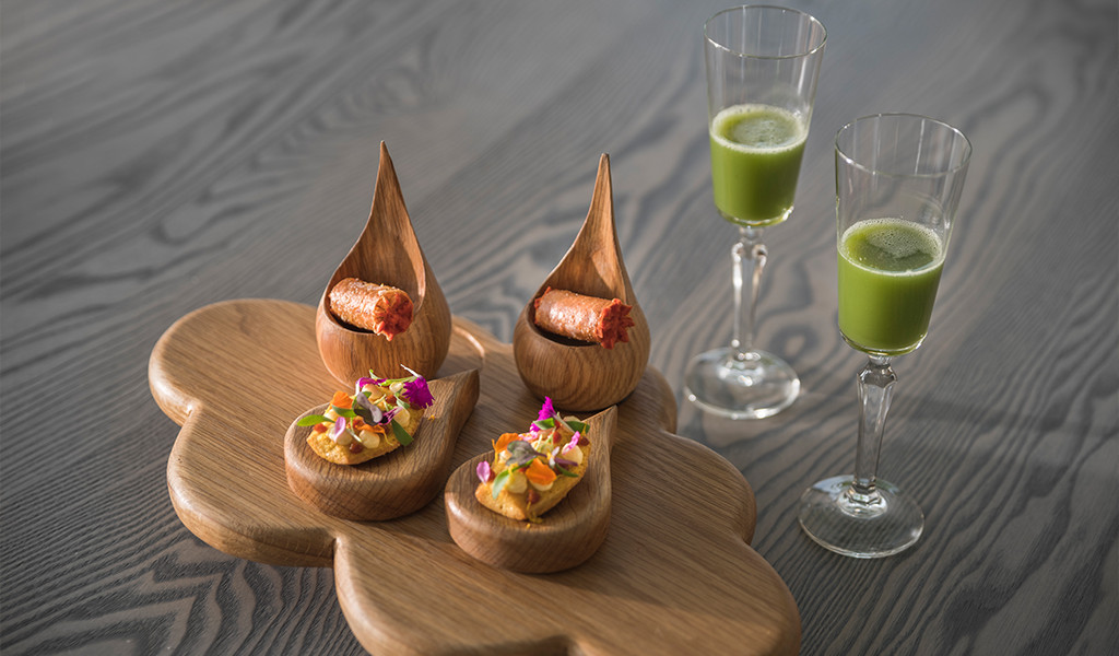 Une variété d’entrées et verres gastronomiques avec du jus vert sur une planche à Tenerife.