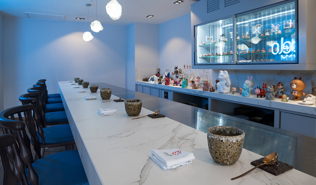 Bar à sushis décoré de figurines et chaises bleues dans un restaurant à Tenerife.