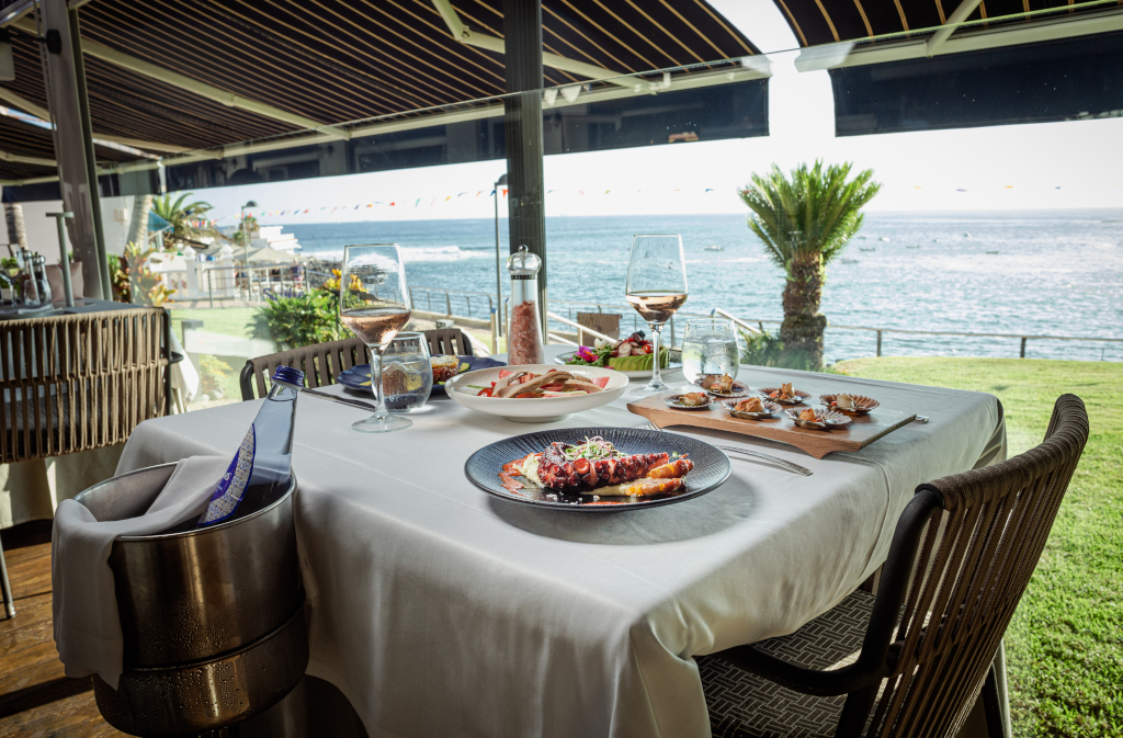 Table de restaurant avec plats gastronomiques et vue sur la mer à Tenerife.