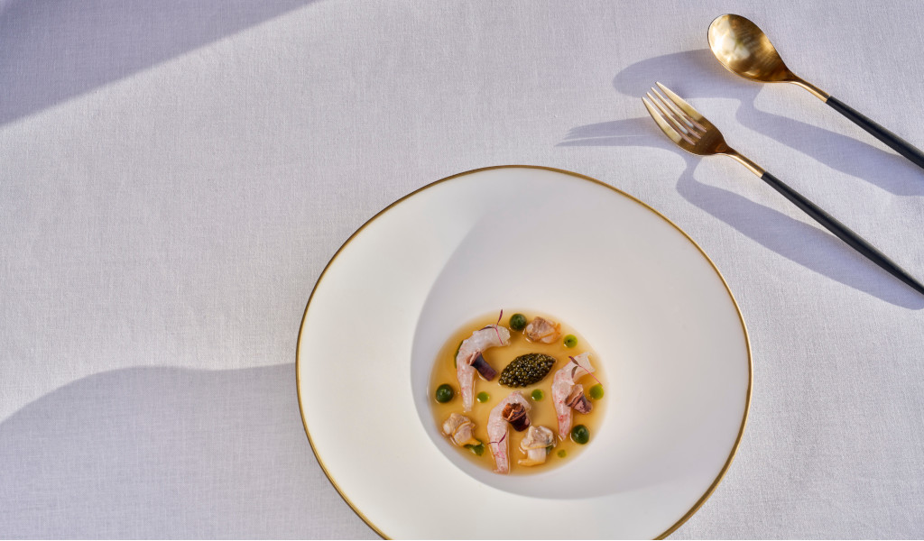 Plat gastronomique aux fruits de mer et sauce sur la table avec des couverts dorés à Tenerife.