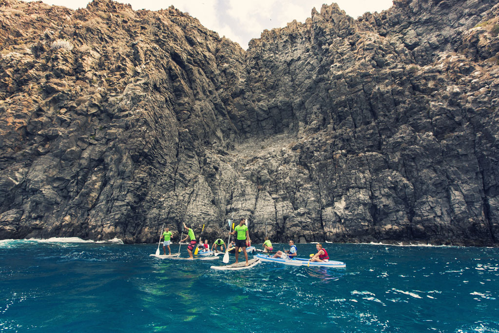 Des gens font du paddle surf devant les falaises à Tenerife.