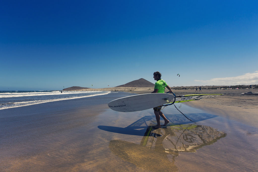 Personne avec une planche de planche à voile sur la plage d’El Médano, Tenerife.