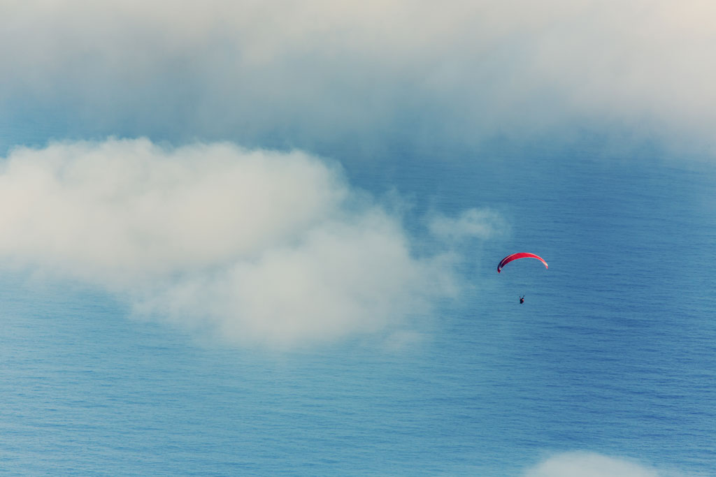 Parapente au-dessus de l’océan à Tenerife parmi des nuages épars.
