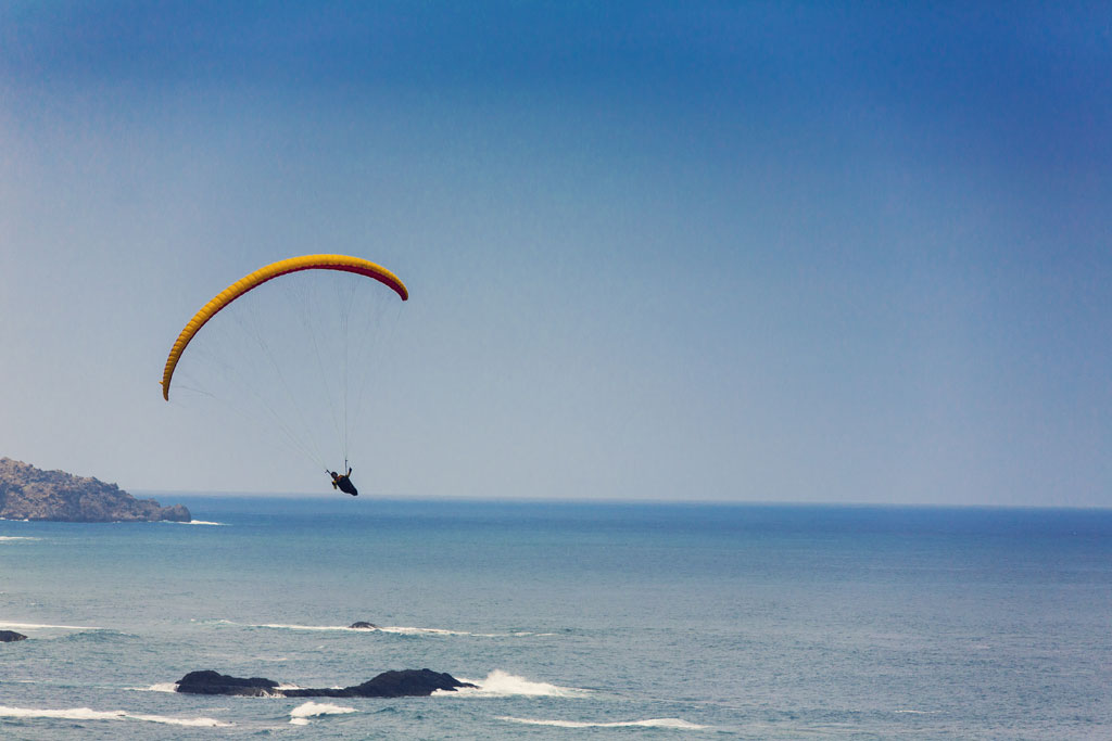 Parapente au-dessus de la côte de Tenerife avec l’océan en arrière-plan.
