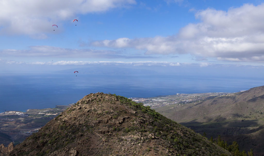 Des parapentes survolant une montagne à Tenerife surplombant l’océan.