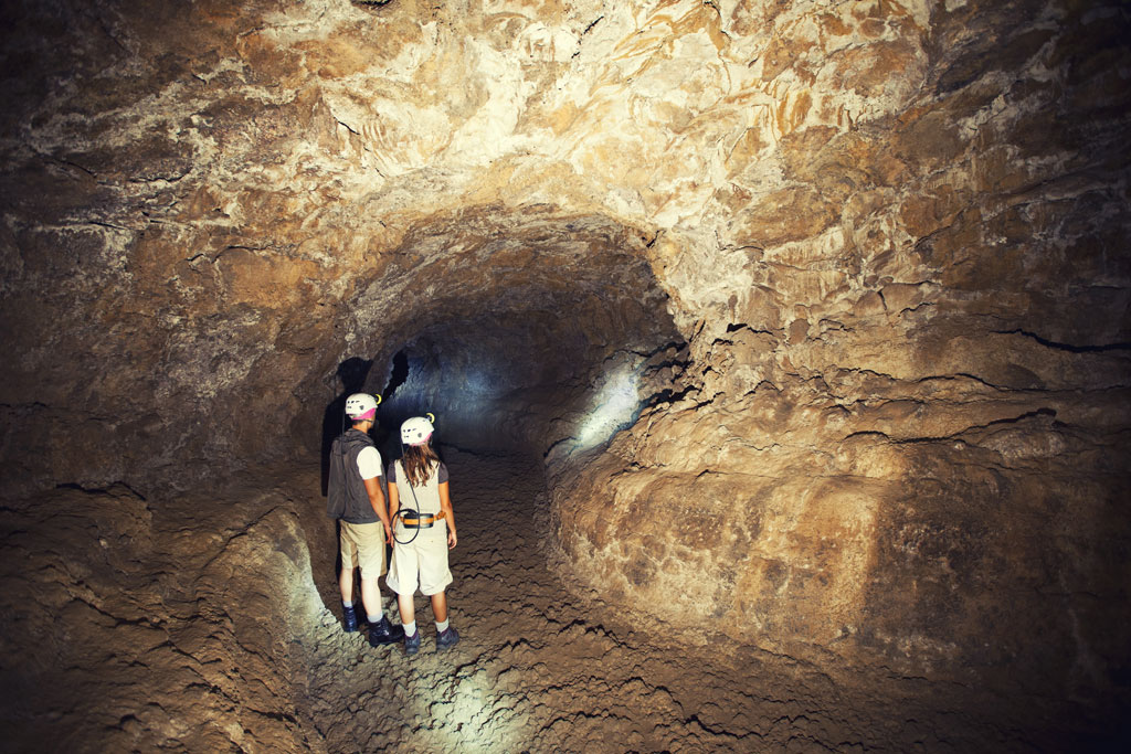 Des explorateurs portant des casques traversent un tunnel à Cueva del Viento, à Tenerife.