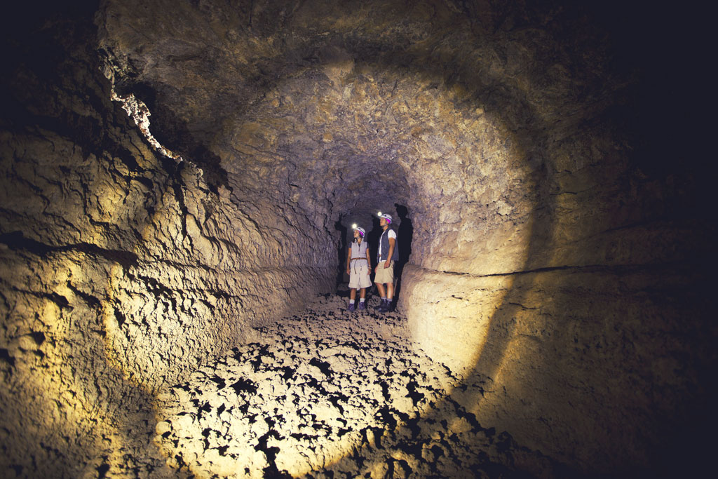 Des explorateurs avec des lampes torches dans un tunnel volcanique à Tenerife.