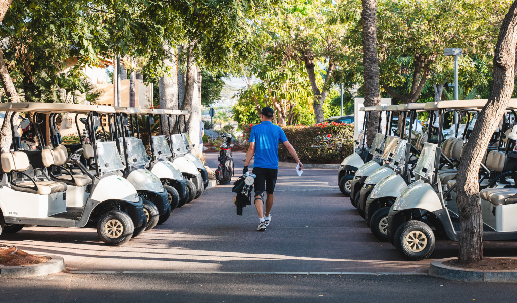 Un homme marche entre des voiturettes de golf garées à Tenerife.