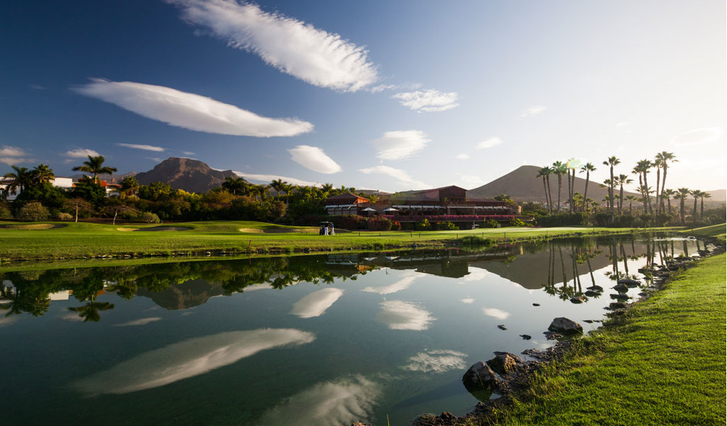 Parcours de golf avec des montagnes et des palmiers reflétés dans un lac à Tenerife.