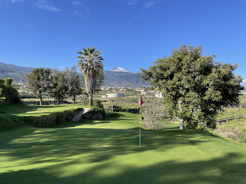 Parcours de golf à Tenerife avec le mont Teide en arrière-plan et un ciel dégagé.