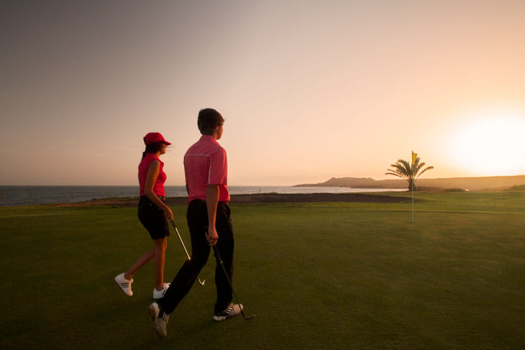 Des gens jouant au golf au coucher du soleil sur la côte de Tenerife.