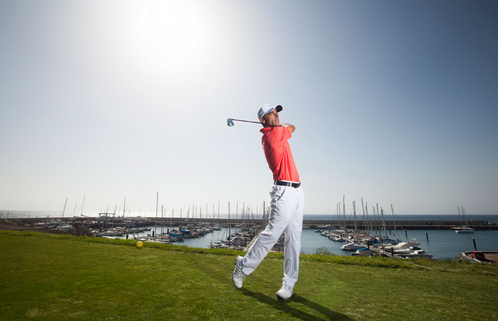 Golfeur lors d’un swing avec la marina et les bateaux en arrière-plan à Tenerife.