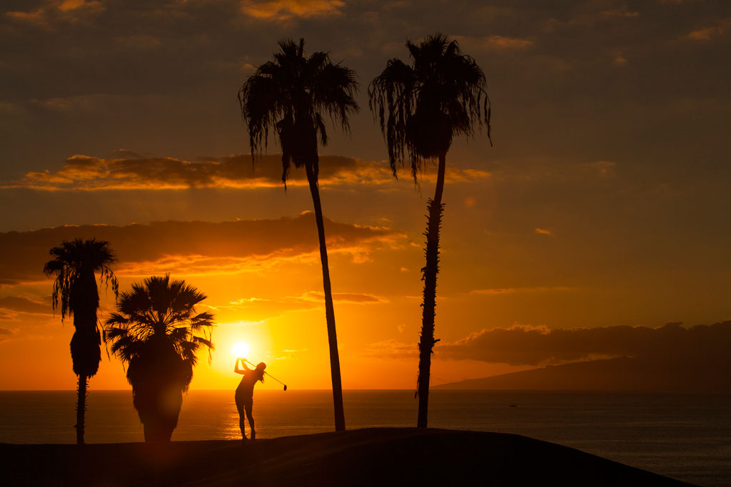 Coucher de soleil avec des palmiers et des joueurs jouant au golf à Tenerife.