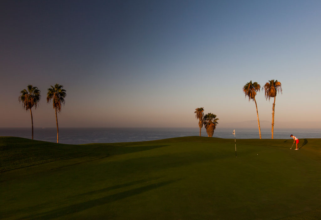 Parcours de golf au coucher du soleil avec des palmiers et joueur à Tenerife.