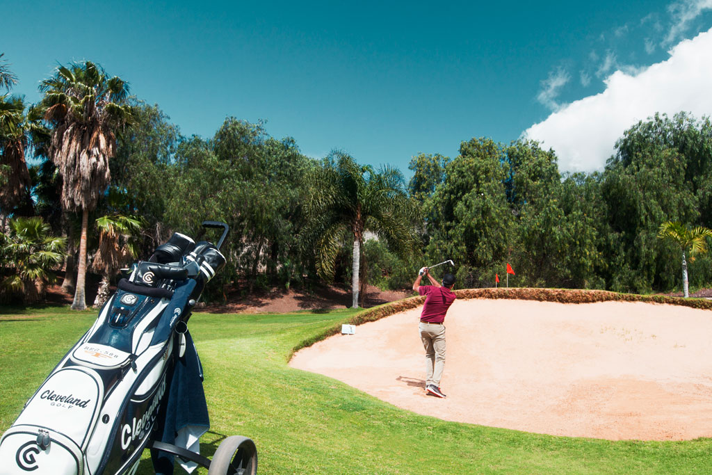 Golfeur en action sur un parcours à Tenerife, près d’un bunker.