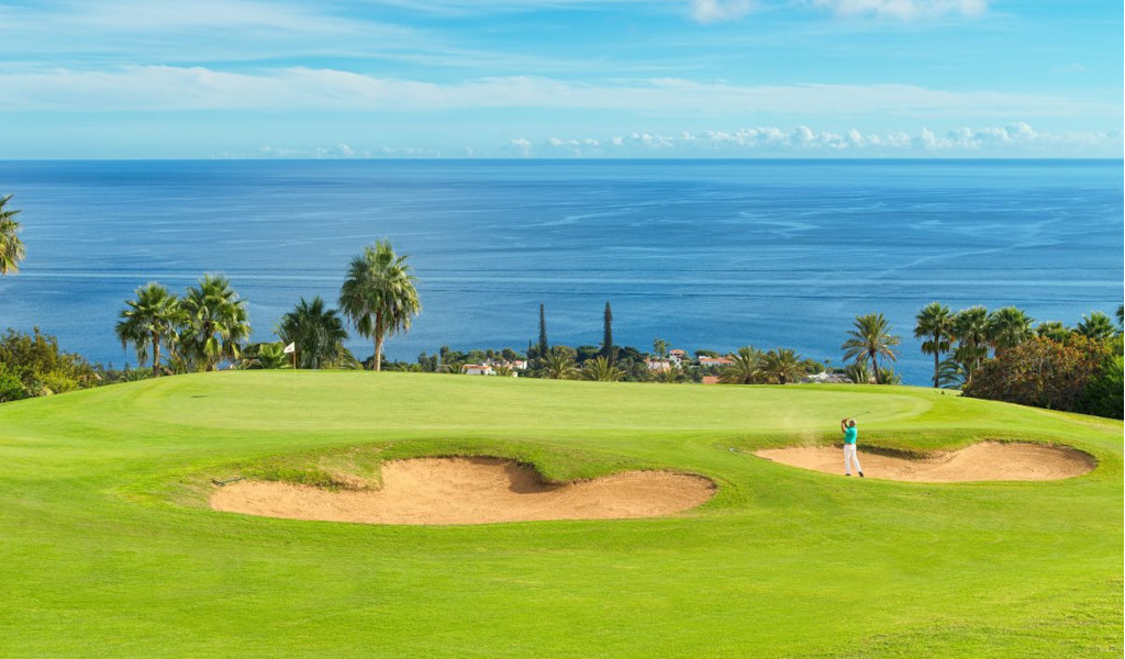 Parcours de golf à Tenerife avec vue sur l’océan. Des coups près des bunkers entourés de palmiers.