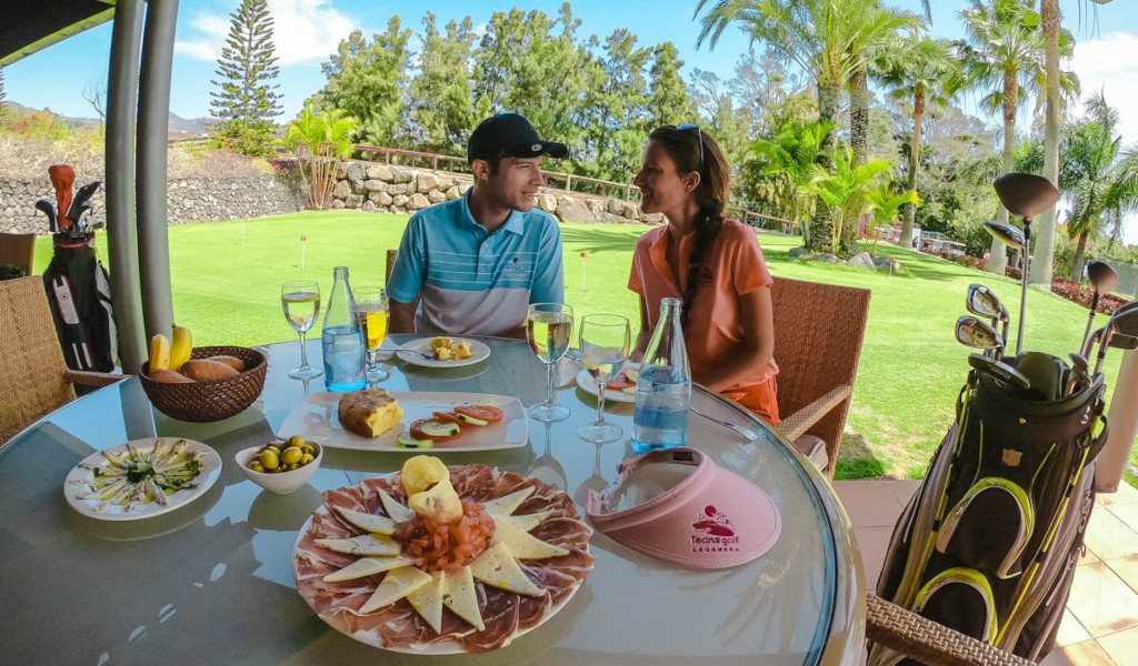 Couple assis avec de la nourriture et des clubs de golf à Tecina Golf, La Gomera, Tenerife.