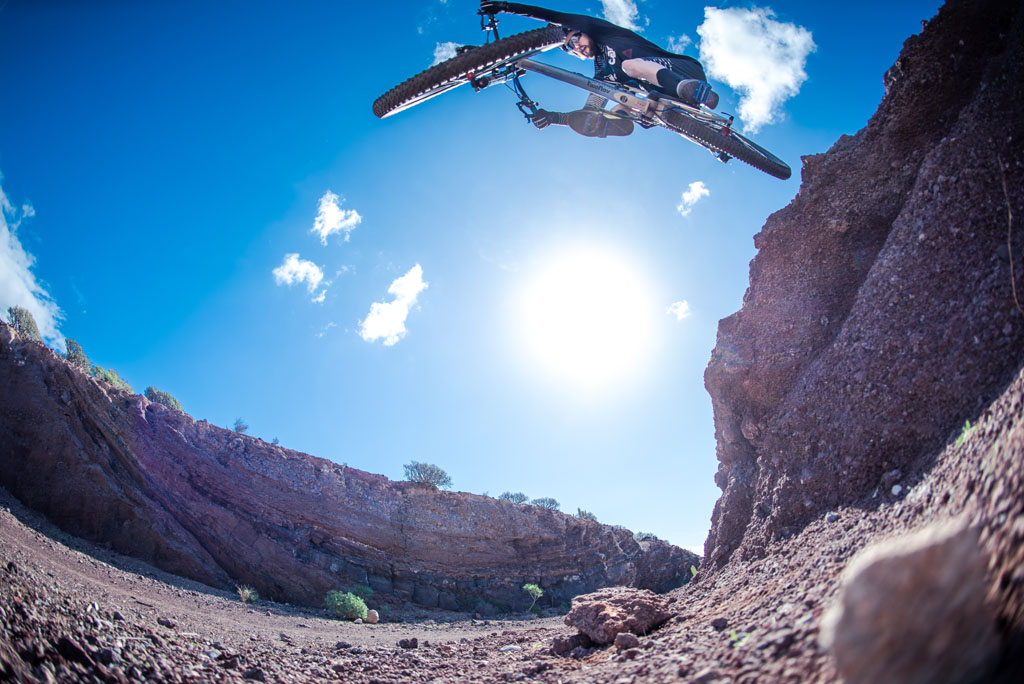 Cycliste en saut extrême dans un canyon à Tenerife sous un ciel dégagé.