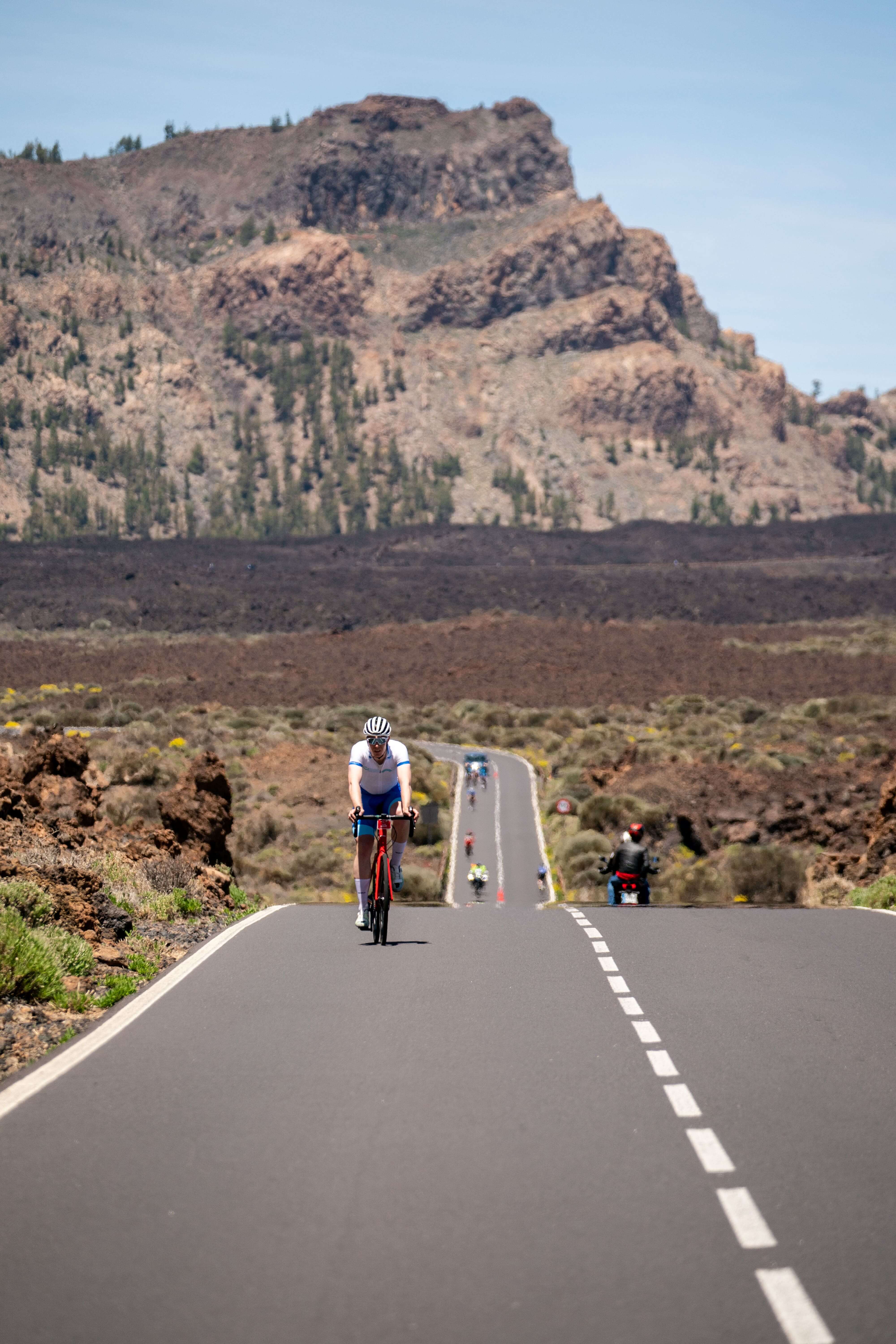 Cycliste sur la route du mont Teide à Tenerife, entourée d’un paysage volcanique.