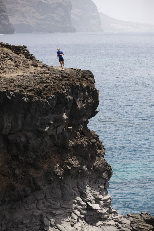 Personne courant sur une falaise à Los Gigantes, Tenerife, avec l’océan en arrière-plan.