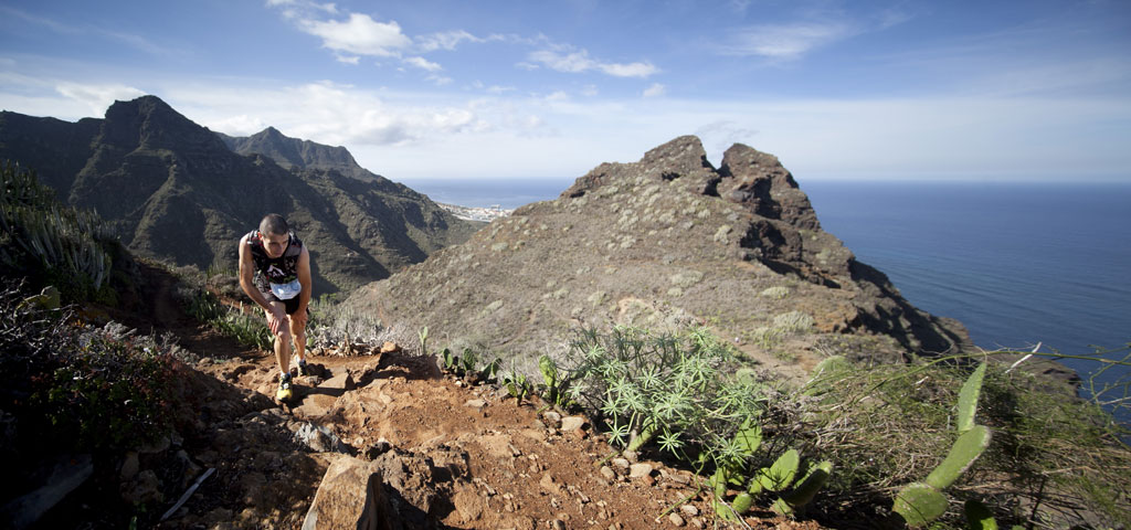 Personne gravissant une colline avec vue sur la mer et les montagnes à Tenerife.