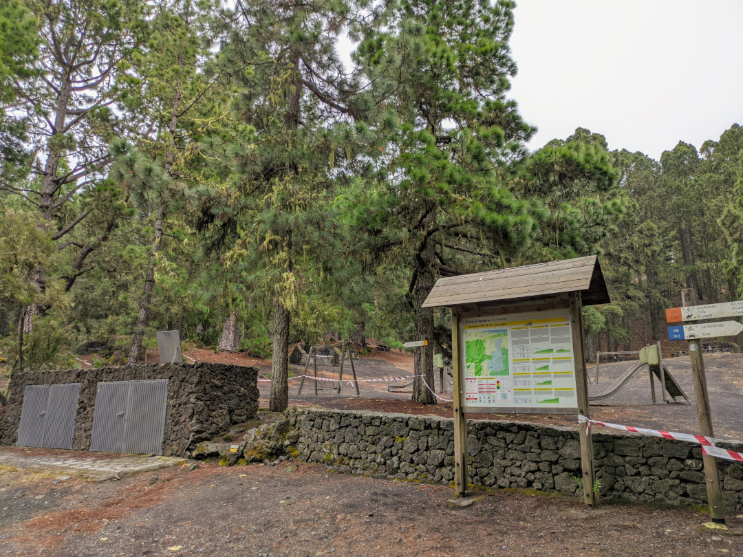 Zone de loisirs avec carte et panneaux à La Esperanza, Tenerife, entourée de pins et de sentiers.