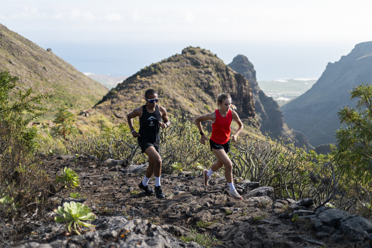 Deux personnes courant le long d’un sentier montagneux à Tenerife avec vue sur la mer.