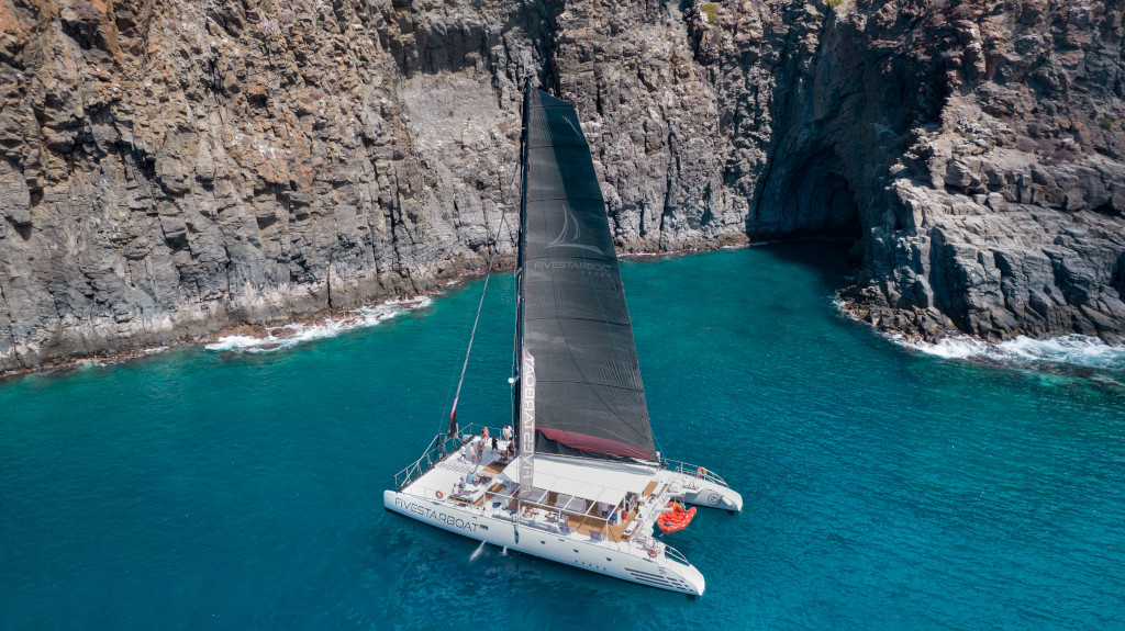 Catamaran naviguant près de falaises rocheuses sur la côte de Tenerife.
