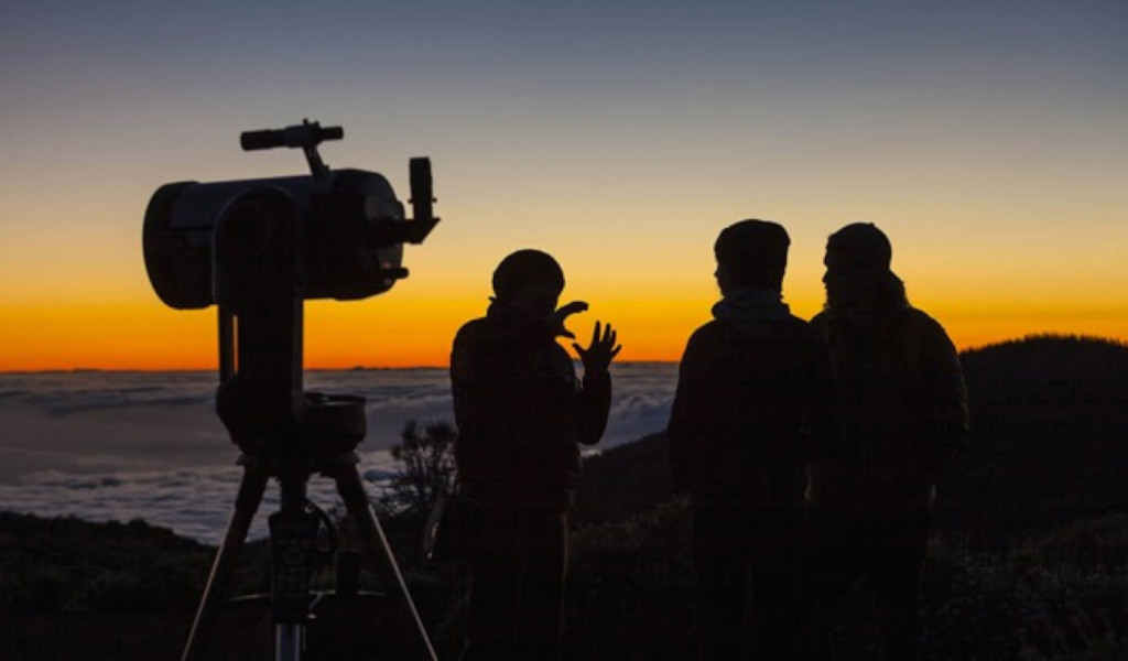 Des gens regardant le lever du soleil avec un télescope à Tenerife.