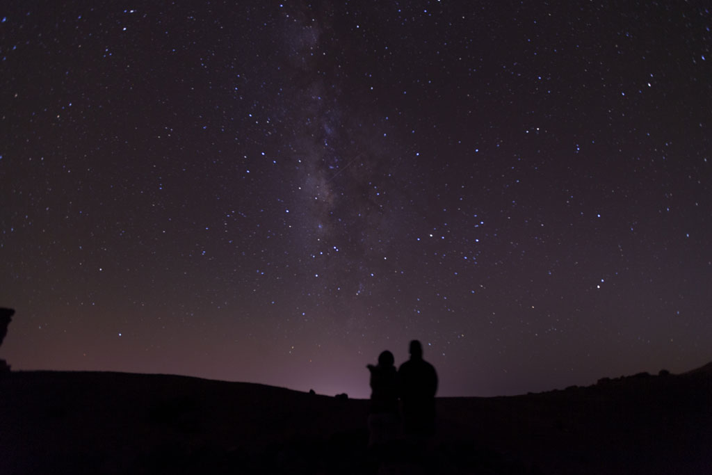 Ciel étoilé au-dessus du mont Teide à Tenerife, avec deux silhouettes observant.