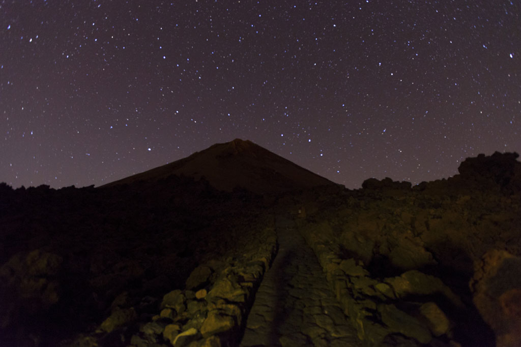 Ciel étoilé au-dessus du mont Teide à Tenerife, avec un chemin rocheux au premier plan.