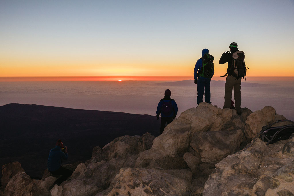 Des alpinistes regardant le lever du soleil depuis le sommet du mont Teide à Tenerife.