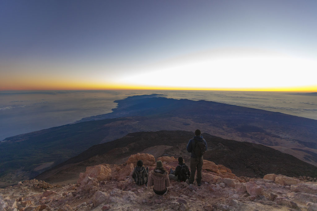 Le lever du soleil sur le mont Teide, à Tenerife, avec des gens observant le paysage depuis le sommet.