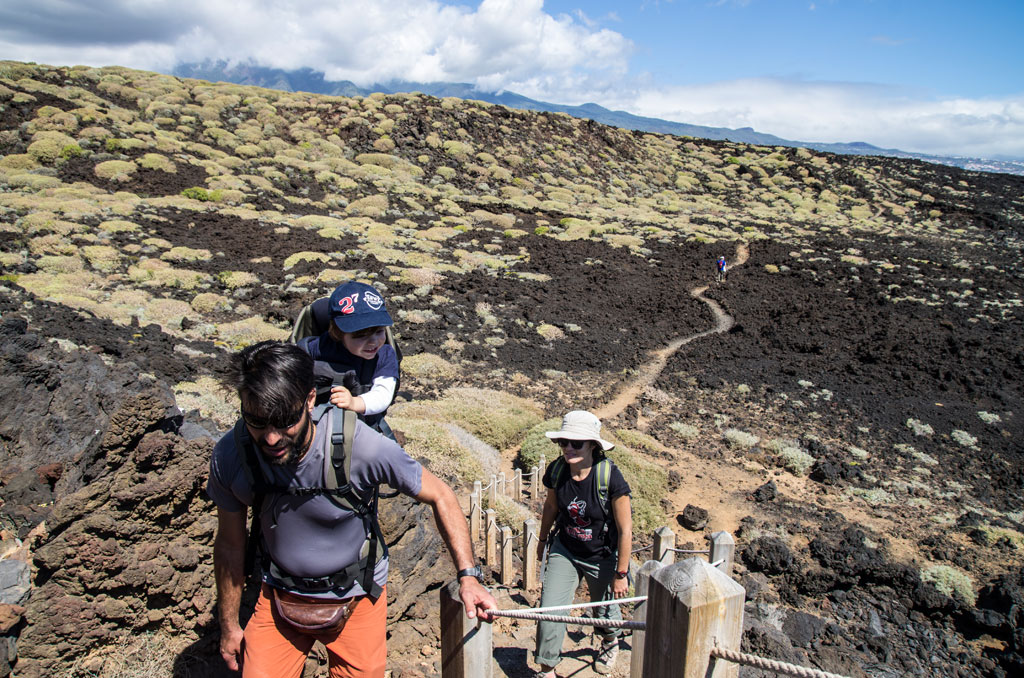 Des gens marchant le long du sentier volcanique à Tenerife sous un ciel partiellement nuageux.