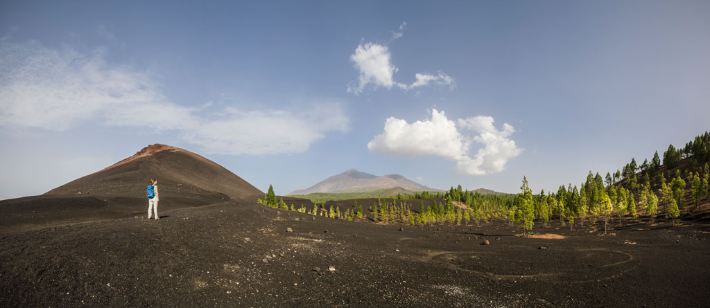 Sentier volcanique dans le parc national du Teide, Tenerife, avec un promeneur au loin.