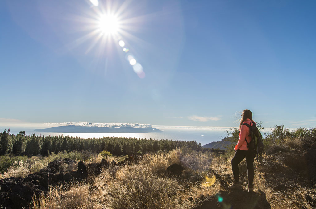 Personne avec un sac à dos contemplant le paysage naturel de Tenerife sous un ciel ensoleillé.